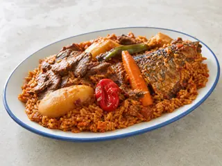 Senegalese thieboudienne with tomato rice, white fish, cassava, cabbage, eggplant, carrot, and okra