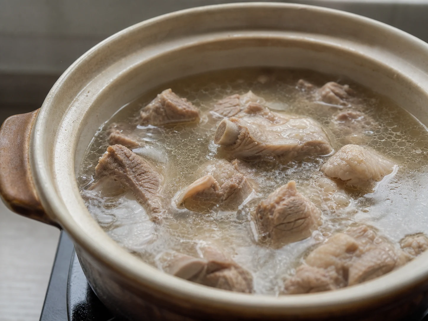 Fully cooked pork ribs simmering in clear pepper broth with softened garlic