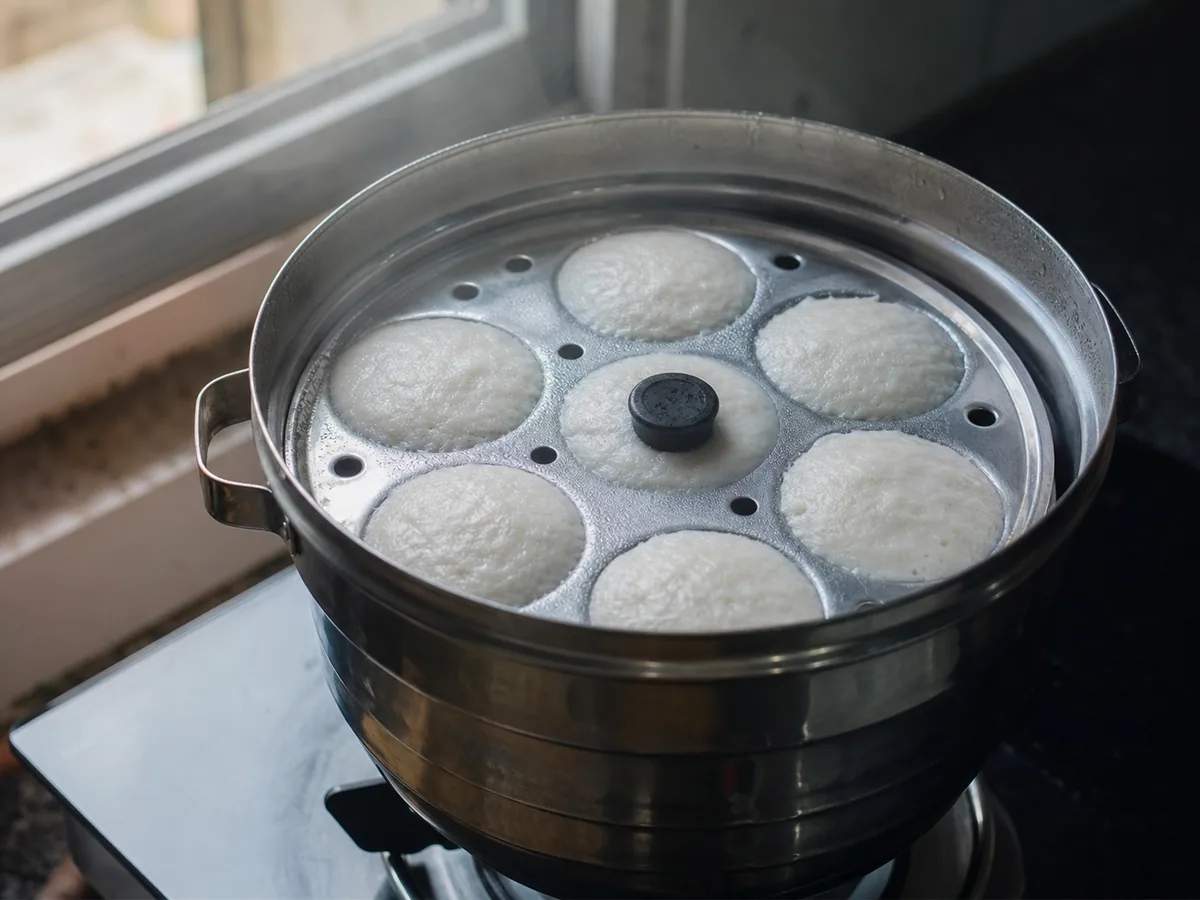 Idlis firmes cozidos no vapor em forma própria, com topos levemente abaulados