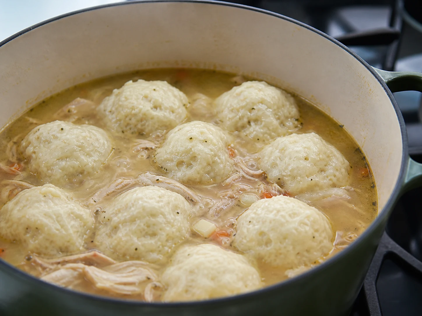 Bolinhos crescidos e totalmente cozidos sobre ensopado de frango em uma panela holandesa