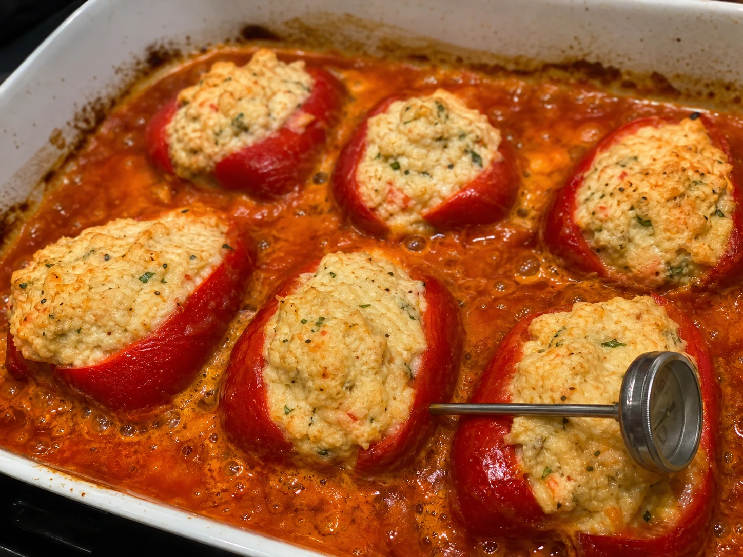 Pimientos del piquillo rellenos de cangrejo ya horneados, con salsa de tomate burbujeante y relleno opaco y caliente