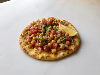 Golden chickpea breakfast flatbreads topped with spiced chickpeas, tomato, red onion, lemon, and cilantro