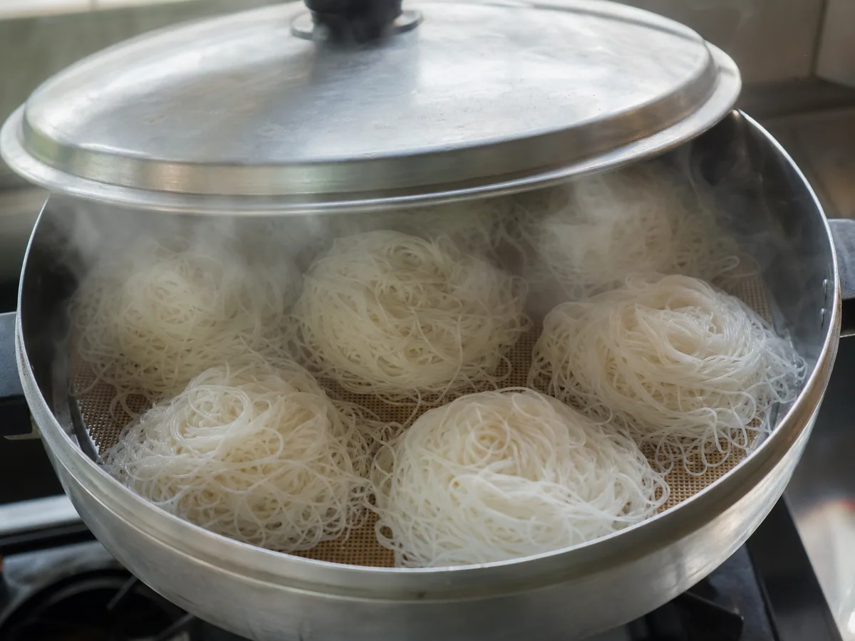 Ninhos de idiyappam do Sri Lanka totalmente cozidos no vapor, soltando-se das esteiras perfuradas