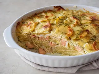 Pudín sueco de salmón y papas con una superficie dorada y eneldo fresco