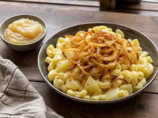 Macarrones alpinos suizos con cubos de patata y cebollas doradas junto a compota de manzana