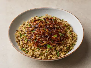 Mujadara siria con lentejas, bulgur y cebollas caramelizadas en una fuente de cerámica