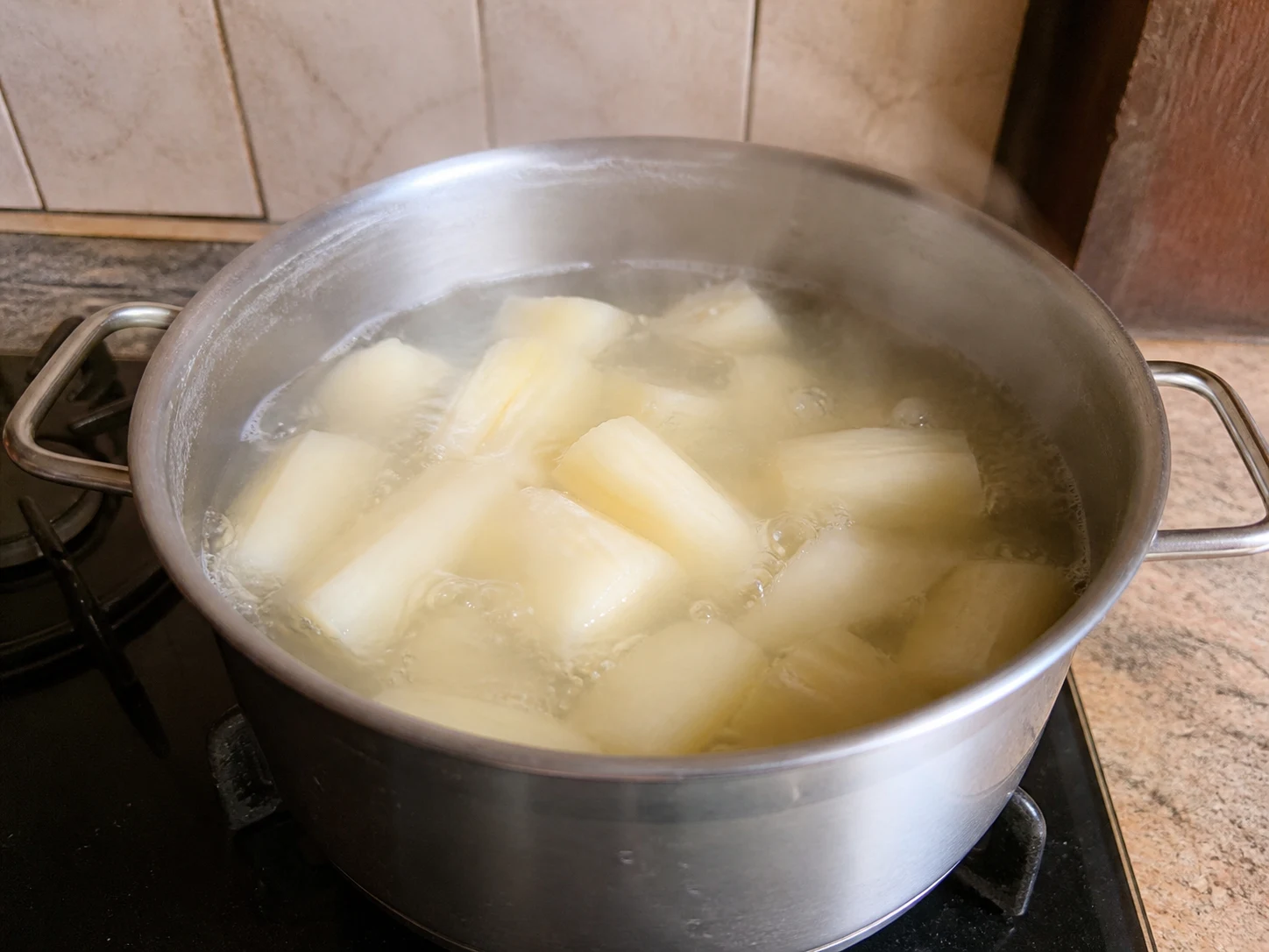 Fork-tender boiled sweet cassava chunks draining before they are added to the curry