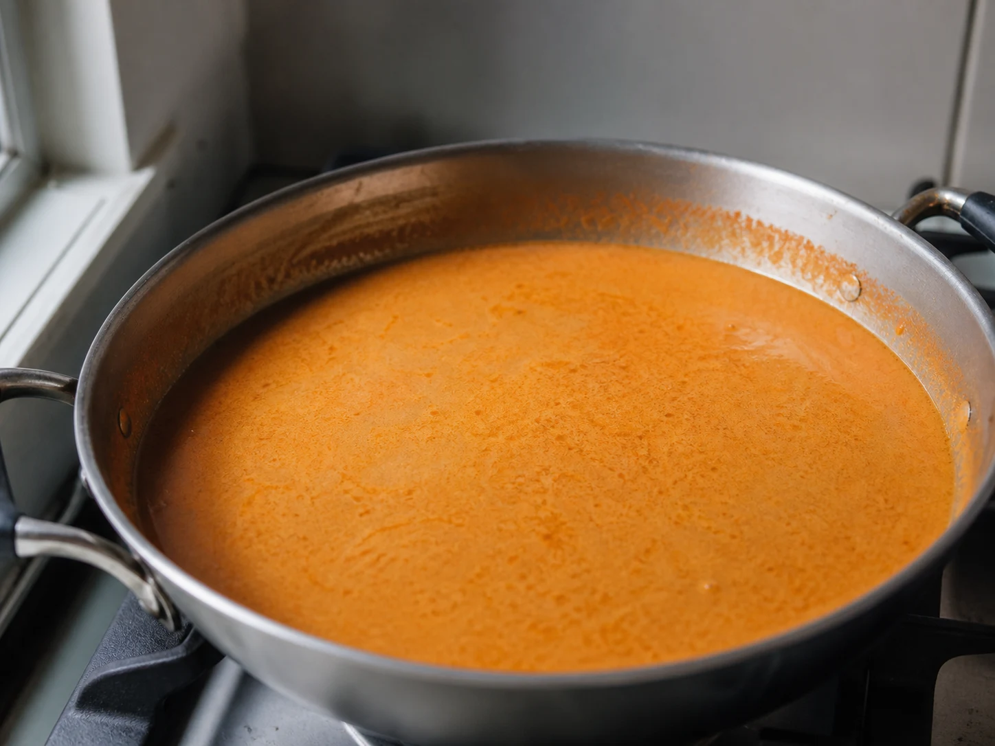 Creamy tomato-coconut sauce simmering before beans and cassava are added