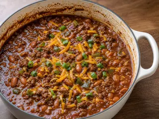 Tigela de chili texano de carne e feijão-pinto coberto com cheddar e cebolinha