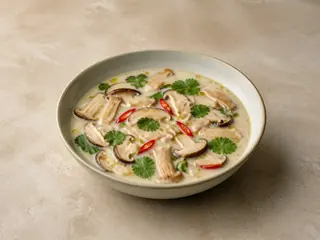 Tazón de sopa tailandesa de coco y champiñones, con cilantro y chile rojo