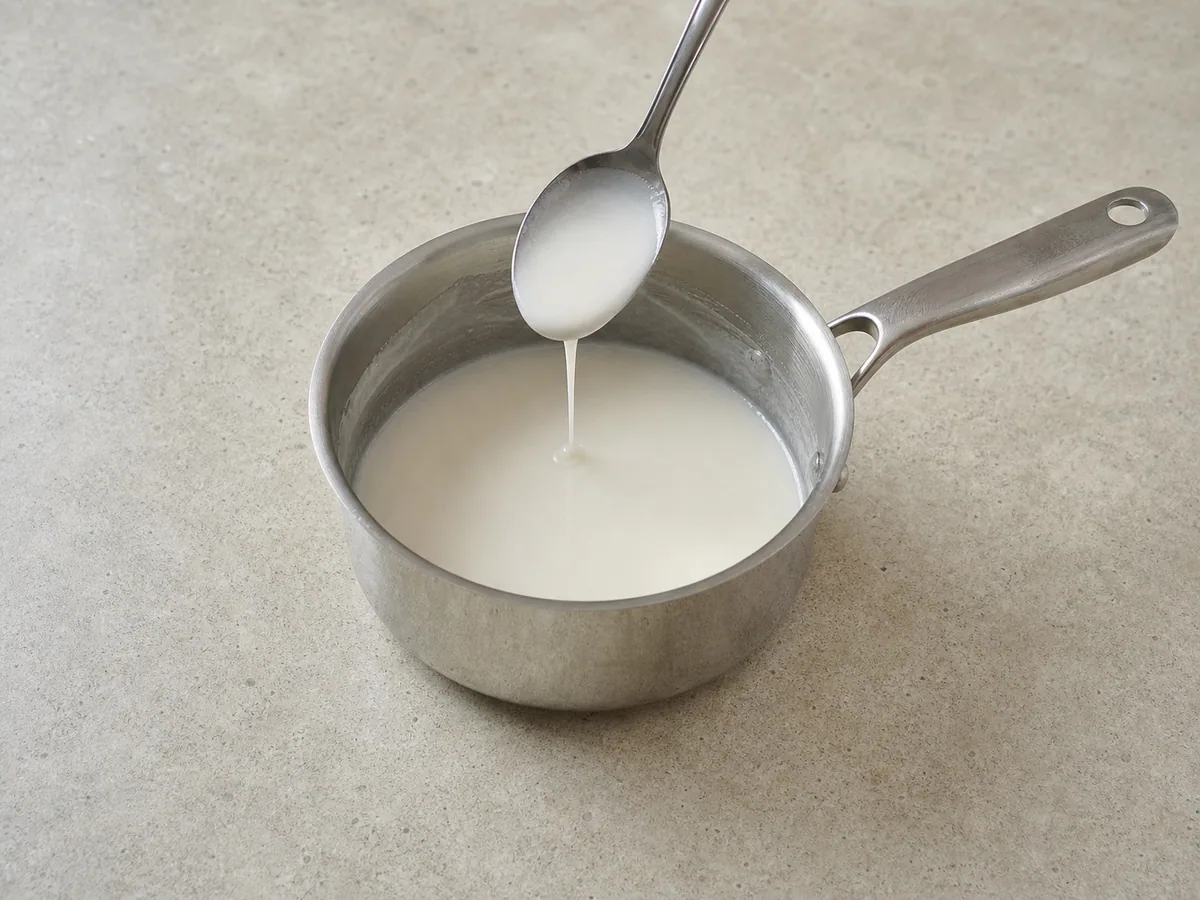 Salsa de coco reservada cubriendo ligeramente una cuchara en una cacerola pequeña