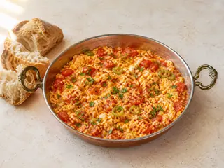Menemen turco con tomates y pimientos verdes en una sartén baja