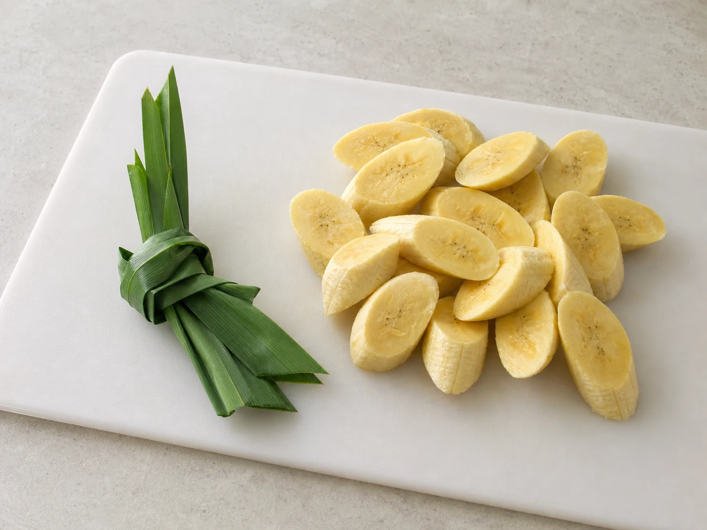 Knotted pandan leaves beside thick diagonal slices of pisang awak banana