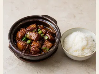 Cerdo vietnamita caramelizado en una olla de barro oscura con cebollines y arroz jazmín