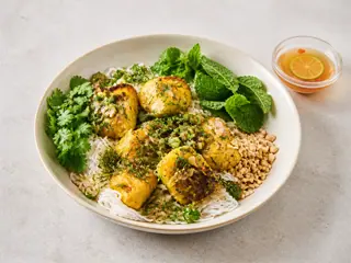 Bacalao con cúrcuma, eneldo y cebollín sobre fideos de arroz, con cacahuates y hierbas