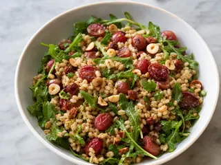 Ensalada tibia de cebada con uvas rojas asadas, rúcula, perejil y avellanas picadas