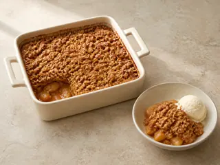 Crujiente de manzana con canela, cobertura dorada de avena y helado de vainilla