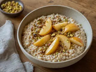 Pilaf caliente de sorgo para desayuno, cubierto con pera glaseada con jarabe de arce y pistachos picados