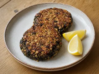 Dois bolinhos galeses de laverbread com crosta crocante de aveia e gomos de limão em um prato de cerâmica